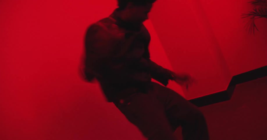 A stylish man and woman dance energetically in a modern room completely saturated in intense red light