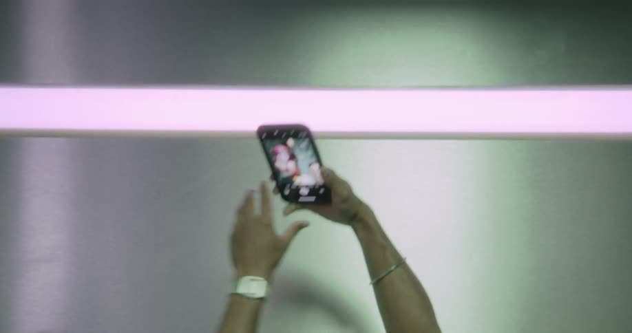 A group of friends takes a fun selfie together with a smartphone in a room with a purple neon light