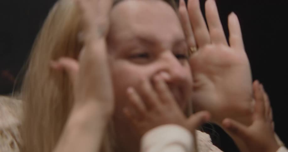 A mother and her baby play a game of peek-a-boo in slow motion, with the mother making a funny, surprised face