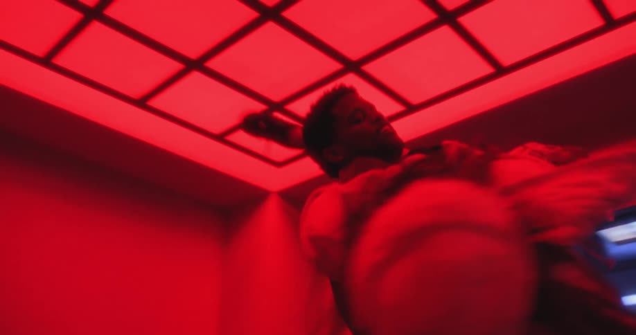 Slow-motion low-angle view of a professional dance couple performing an intense routine in a red-lit hallway