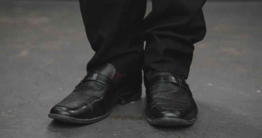 A close-up shot on the feet of a man in black dress shoes who is nervously tapping his foot