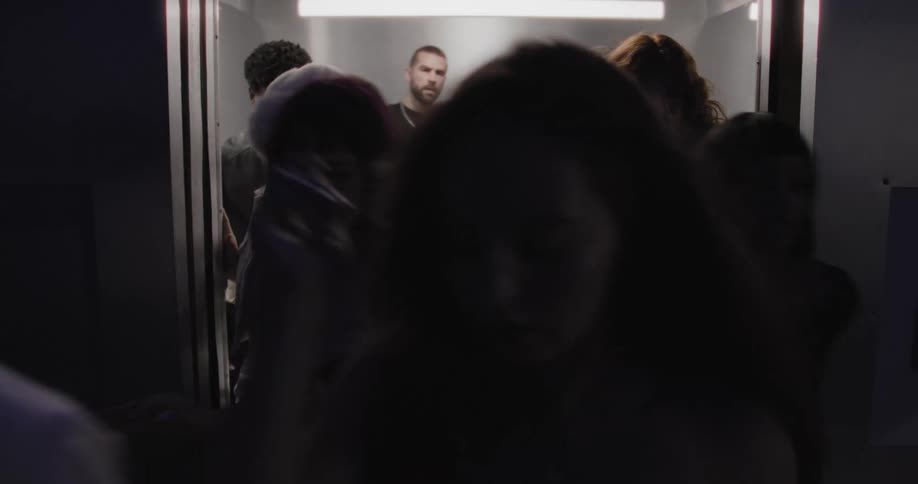 A diverse crowd of people exits a crowded elevator in a continuous stream until it is left completely empty