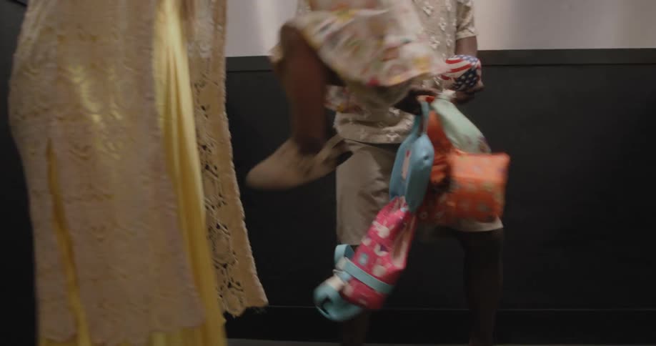 A playful mixed-race family dances and has fun together in an elevator on their way to go swimming in slow motion