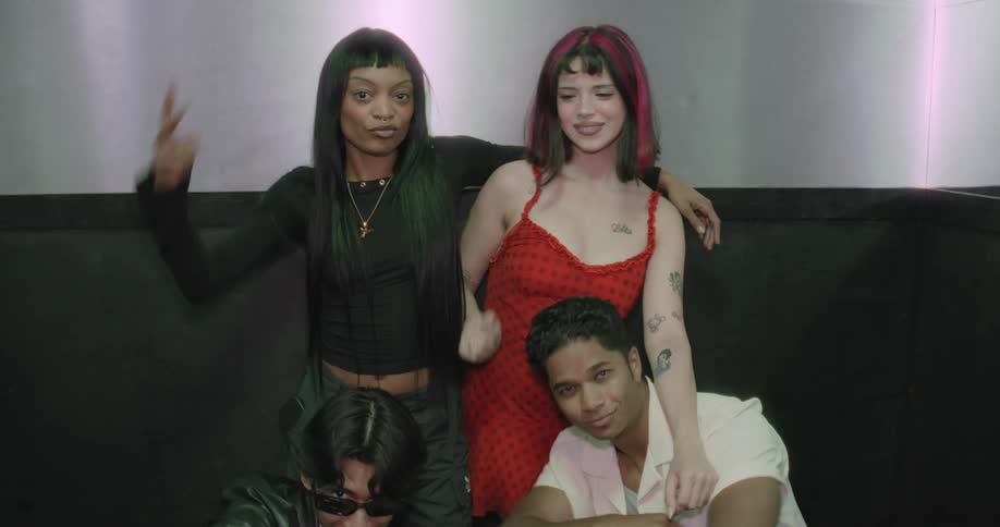 A group of young, fashionable friends pose playfully in an industrial-style elevator as the camera pulls back