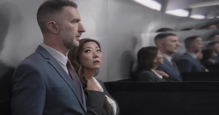 Anxious businesswoman fidgets while sitting next to a serious male colleague in a conference audience