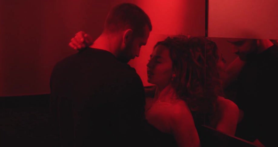 A passionate couple embraces and kisses intimately in a dark room bathed in intense red light