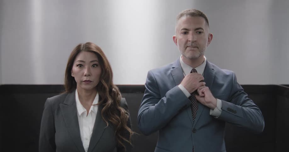 Bored business professionals, a man and a woman, wait impatiently in a slow-moving elevator