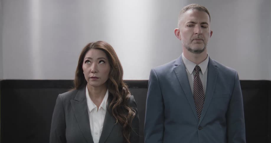 Bored and impatient business colleagues in suits roll their eyes while riding a slow elevator