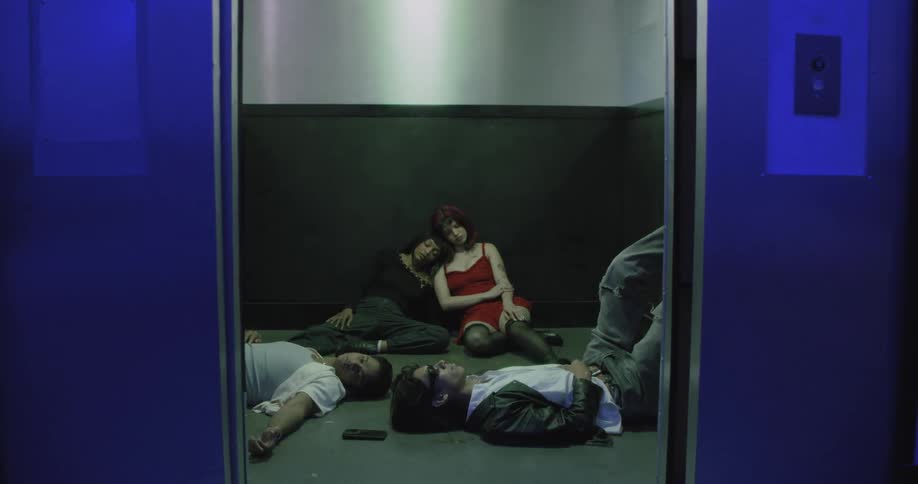 Elevator doors open to reveal a group of friends passed out on the floor in a blue-lit hall