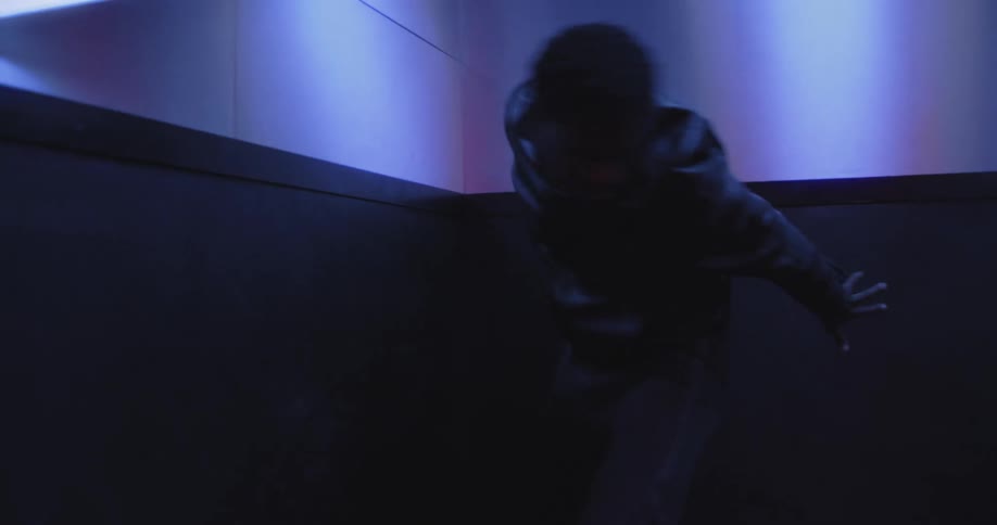 Two stylish dancers perform an intense, modern dance routine in a dramatically lit elevator and hallway