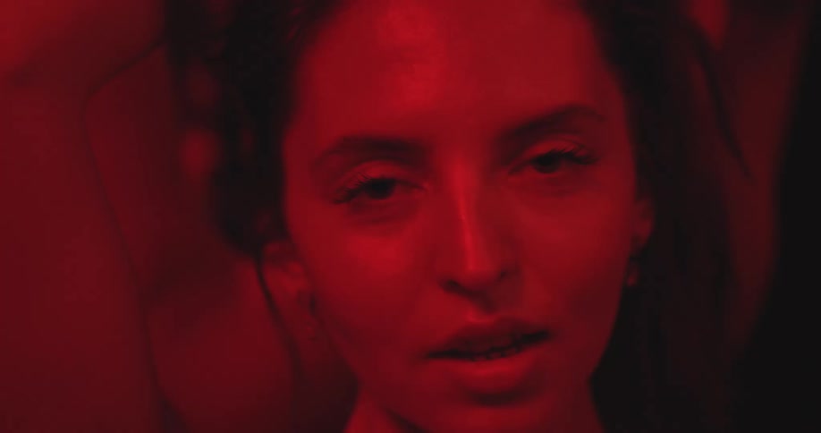 An alluring woman gazes seductively at the camera in an intimate slow-motion portrait bathed in dramatic red light