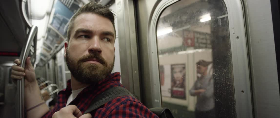 Man sits on a moving train watching out the window