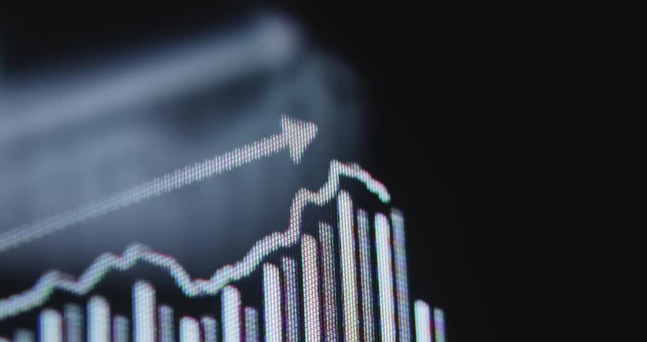 A macro close-up of a digital screen shows an animated financial chart with a positive upward trend