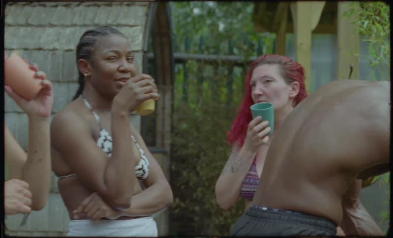 A diverse group of friends in swimwear enjoy drinks and laughter together in a relaxed outdoor setting