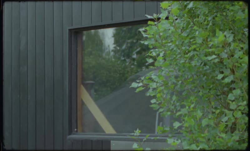 A slow tilt down reveals people enjoying a relaxing session inside a modern, secluded garden sauna