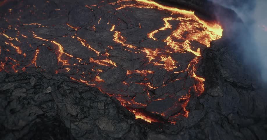 A dramatic close-up of molten lava flowing and hardening into volcanic rock as smoke rises