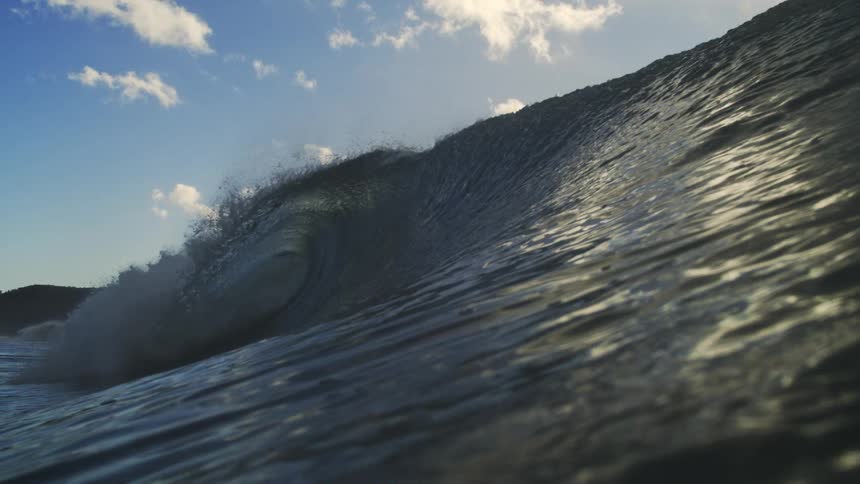 A dramatic slow-motion close-up of a powerful ocean wave cresting and forming a barrel as the camera slowly sinks underwater