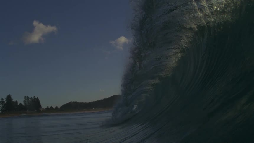 An incredible super slow-motion view from inside the barrel of a powerful ocean wave as it curls towards a distant shore