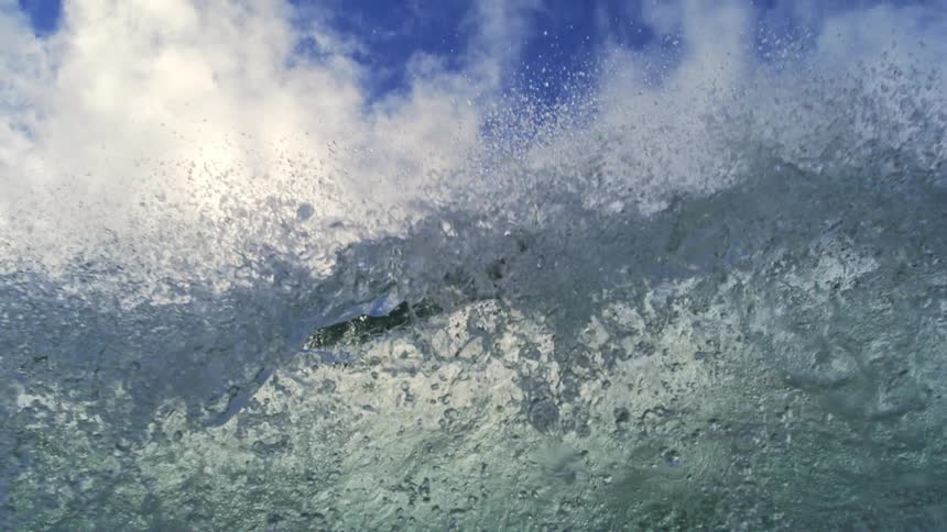 A super slow-motion view from below as a powerful ocean wave crests and crashes over the camera, creating a chaotic underwater scene