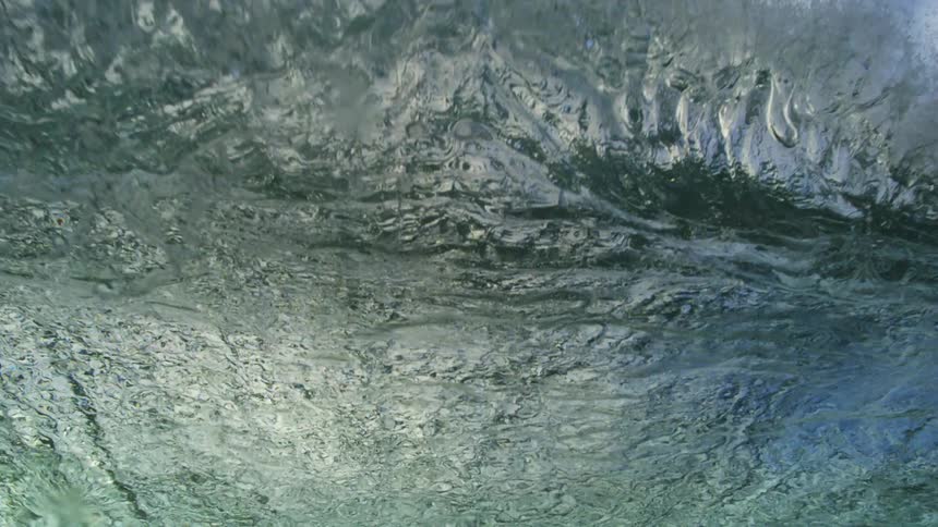 An immersive underwater view captures a massive ocean wave cresting and breaking in extreme slow motion