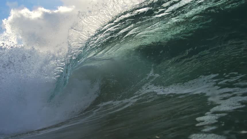 A mesmerizing slow-motion close-up of a powerful ocean wave cresting and barreling under a cloudy sky