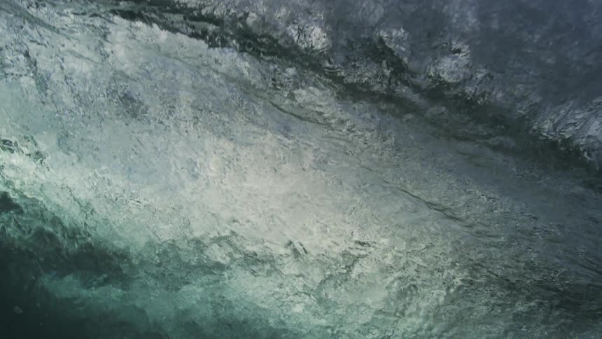 A powerful ocean wave crests and breaks in dramatic super slow motion as viewed from underwater