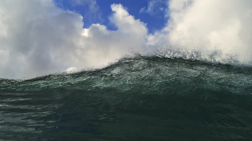 A powerful ocean wave builds in dramatic slow motion before the view submerges beneath the turbulent surface