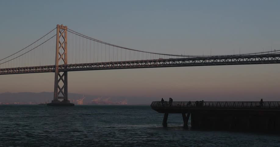 The iconic Bay Bridge in San Francisco stands majestically over the water during a beautiful sunset