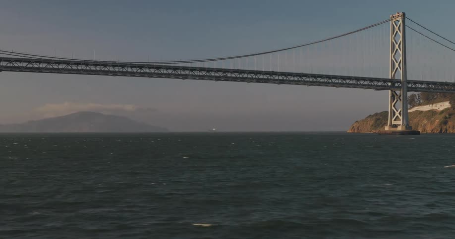 A cinematic slow approach towards the iconic San Francisco-Oakland Bay Bridge from across the bay waters