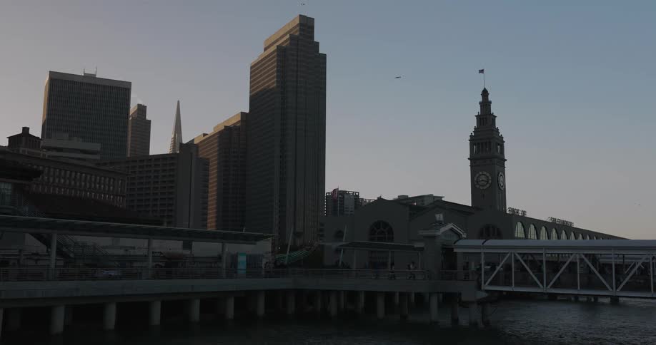 A tranquil static shot of the San Francisco Ferry Building and downtown skyline during a beautiful sunset