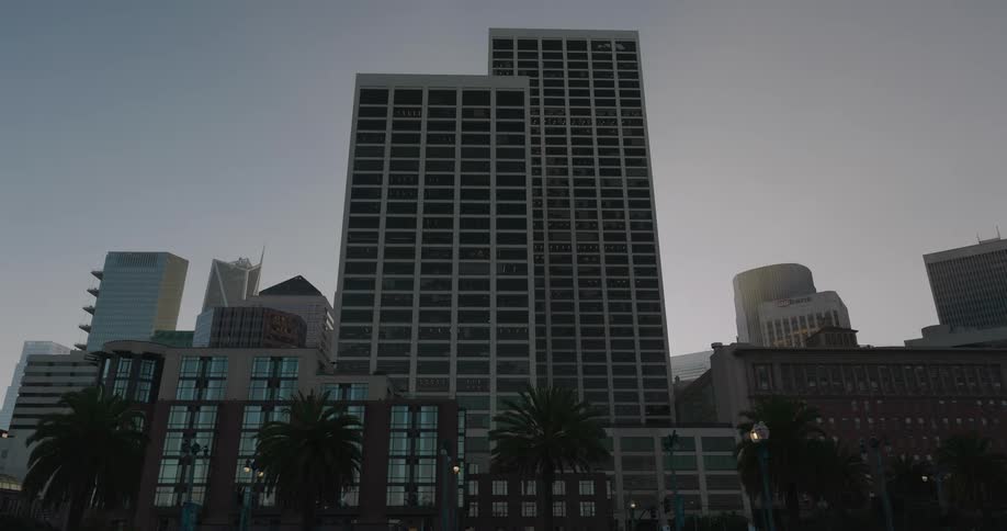 A static, low-angle view of city skyscrapers and buildings against a clear sky during twilight