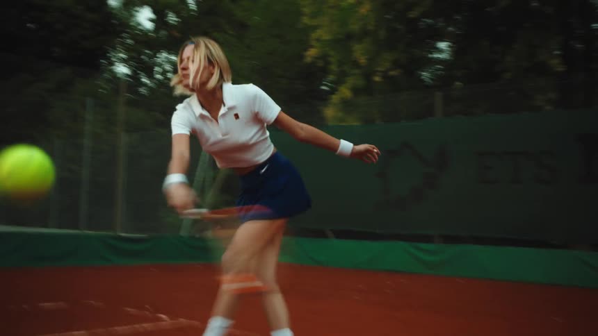 Close-up slow motion with motion blur of a female athlete hitting a powerful tennis forehand