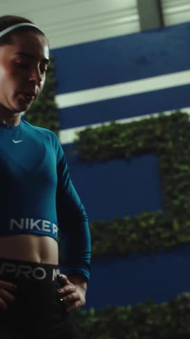 A tired but determined female athlete takes a break from her intense training session in a modern gym