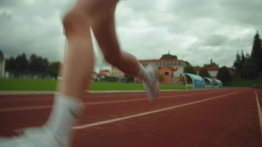 A dynamic low-angle view of a female athlete's powerful legs running on a professional track during training