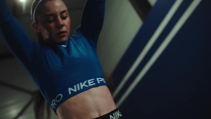 Low angle shot of a focused female athlete doing wall ball throws during a high-intensity workout