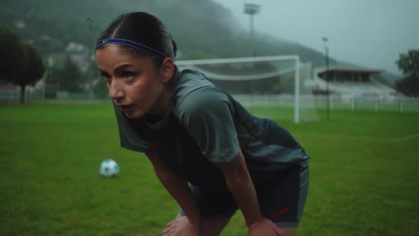 Slow motion of a determined female soccer player catching her breath on a misty field during a grueling practice