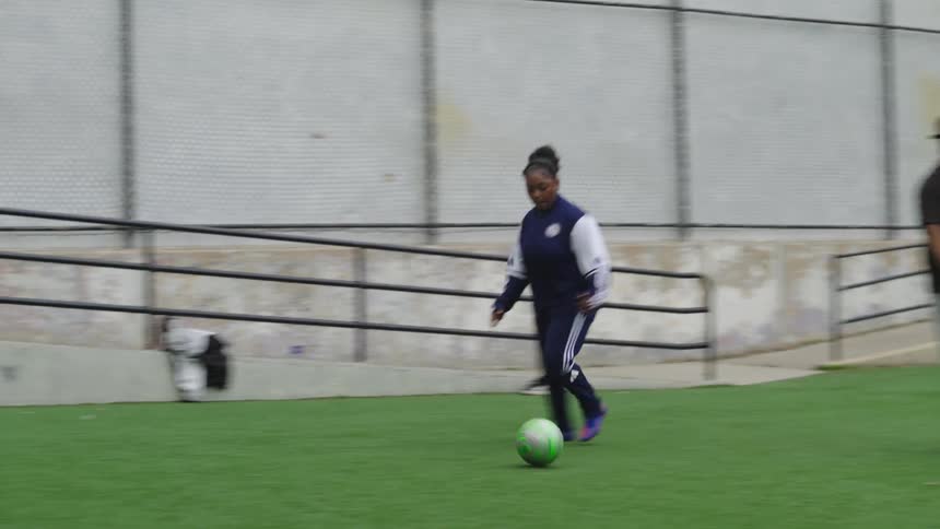 A female youth soccer player kicks a powerful shot on goal, which is saved by the goalkeeper during practice in slow motion