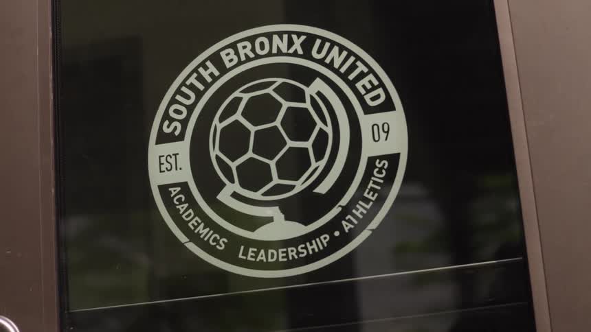 A close-up shot of the South Bronx United logo on a glass door with a slight zoom