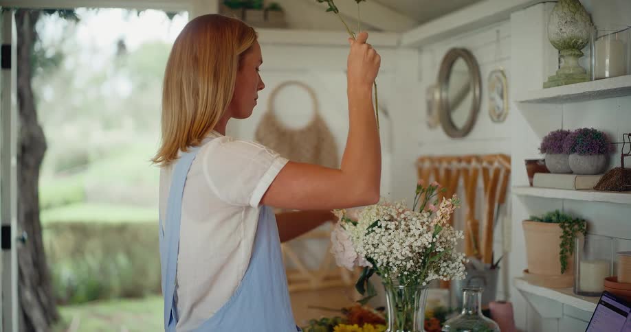 Slow motion shot of a florist carefully arranging a beautiful bouquet of flowers in her cozy, rustic workshop