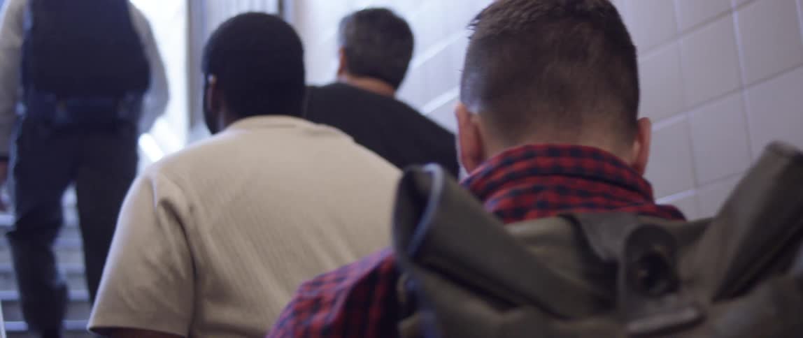 Close up of a man walking up some stairs wearing a backpack
