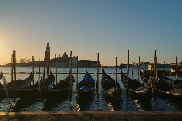 Iconic view of traditional gondolas bobbing in the canals of Venice, Italy during a beautiful sunrise