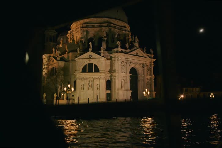 A majestic view of the Basilica di Santa Maria della Salute at night, framed from across the Grand Canal in Venice, Italy