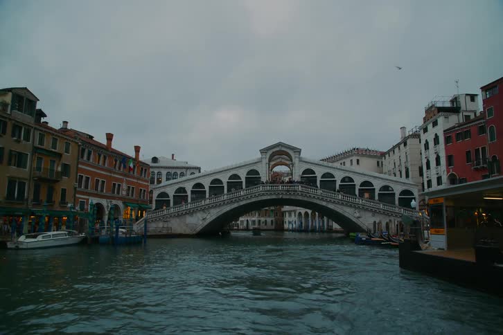An iconic view of the Rialto Bridge over the Grand Canal in Venice during a cloudy evening