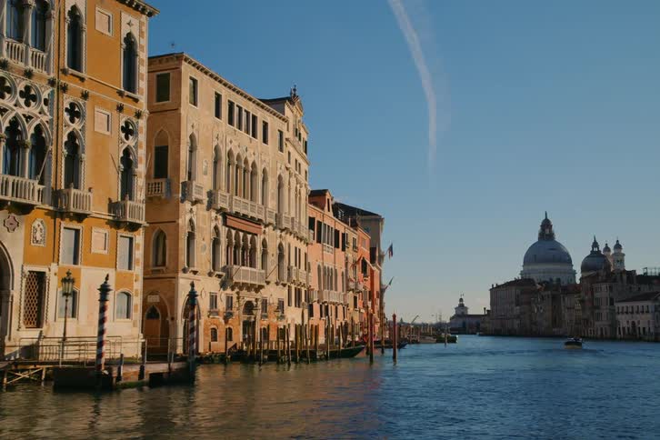 A serene journey along the Grand Canal in Venice, passing by historic architecture under a clear blue sky