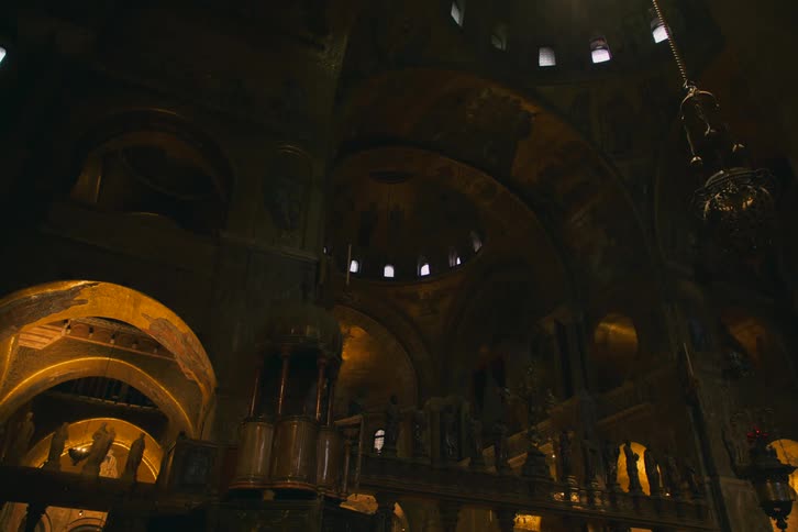 Sunbeams illuminate the magnificent golden mosaic ceilings and ornate architecture inside a historic European cathedral