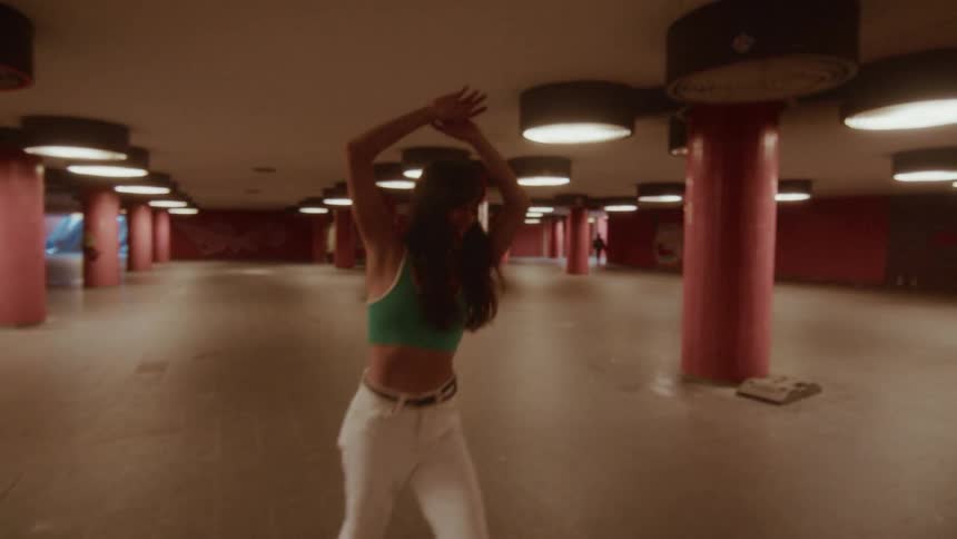 A young woman dances joyfully and freely in slow motion in a graffiti-covered urban underpass