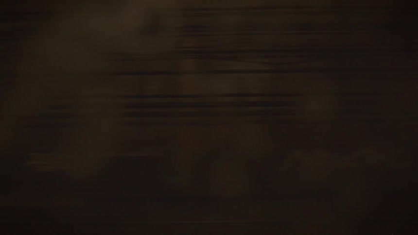 A seamless loop captures the abstract, motion-blurred view of a speeding subway train in a dimly lit underground station