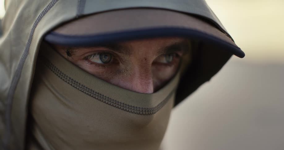 An intense close-up shot of a man's determined eyes, wearing a hood and face covering