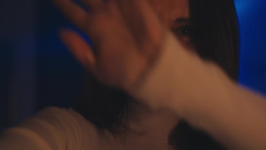 POV shot of a smiling woman dancing freely at a party with flashing blue and green lights