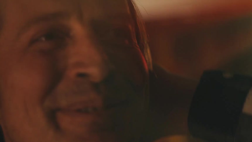 An intimate and emotional close-up of a smiling man enjoying a moment at a party with colorful flashing lights